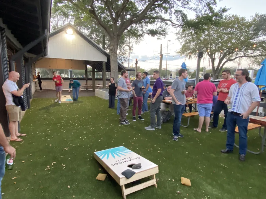A bunch of Drupalers playing cornhole at an afterparty event